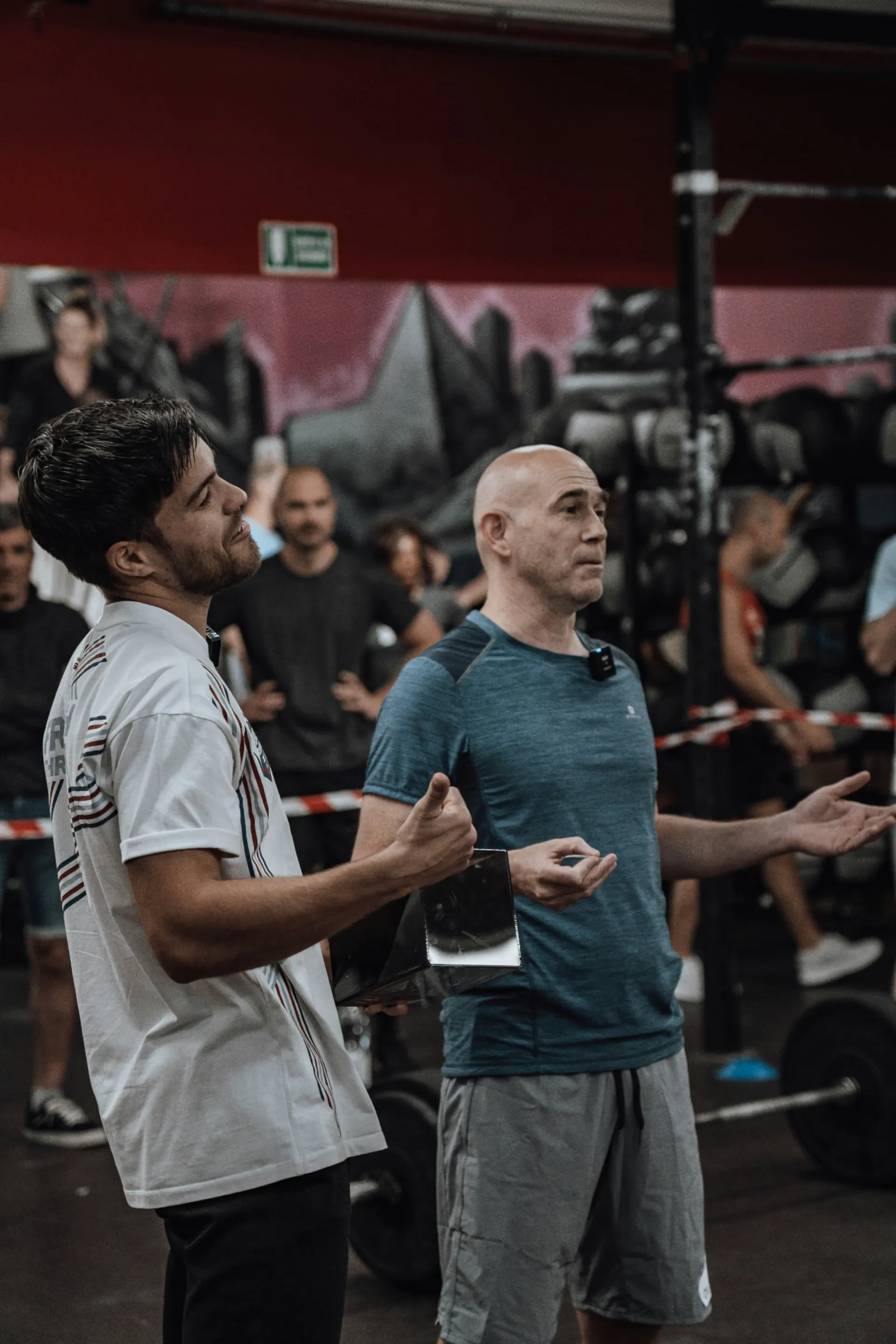 Coach sportif expérimenté partageant ses conseils à un jeune coach dans une salle de sport